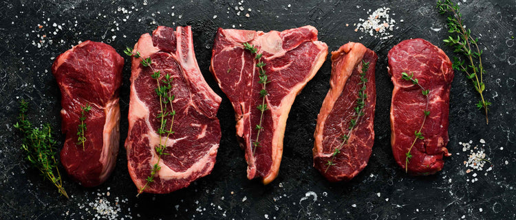  variety of 5 cuts of premium beef arranged on a slate board with salt and herbs